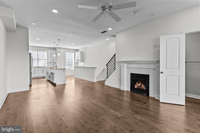 unfurnished living room with ceiling fan, dark wood-style flooring, recessed lighting, a fireplace, and baseboards