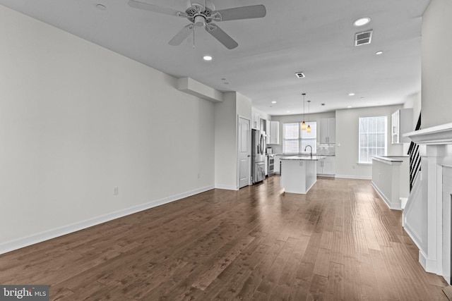 unfurnished living room with dark wood-style floors, recessed lighting, a ceiling fan, and baseboards