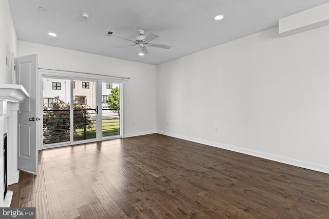 unfurnished room featuring dark wood-style floors, ceiling fan, a fireplace, baseboards, and recessed lighting