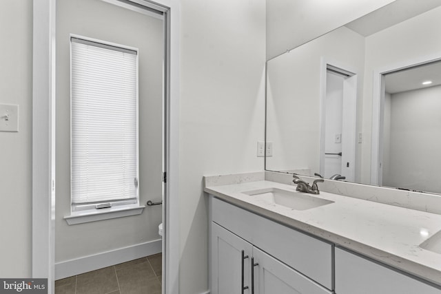 bathroom with toilet, vanity, tile patterned flooring, and baseboards