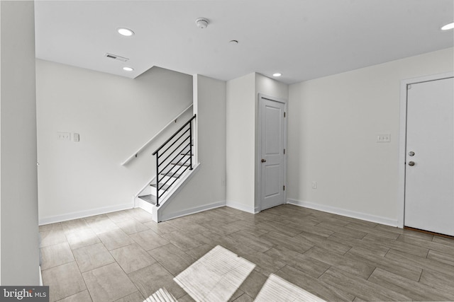 spare room featuring stairway, recessed lighting, wood finish floors, and baseboards