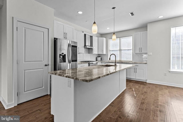 kitchen with stainless steel appliances, a sink, wall chimney exhaust hood, dark wood-style floors, and stone countertops