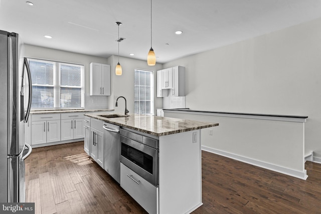 kitchen with stainless steel appliances, a sink, dark wood-style floors, light stone countertops, and recessed lighting