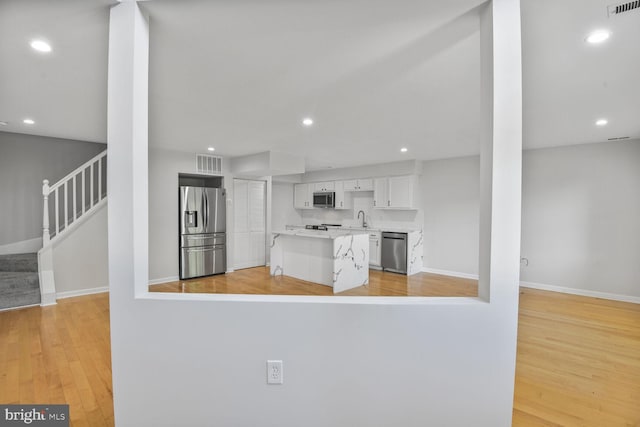8118 Chapel Cove Dr, Laurel, MD 20707 - kitchen featuring stainless steel appliances, a sink, white cabinetry, light wood-style floors, and a kitchen island