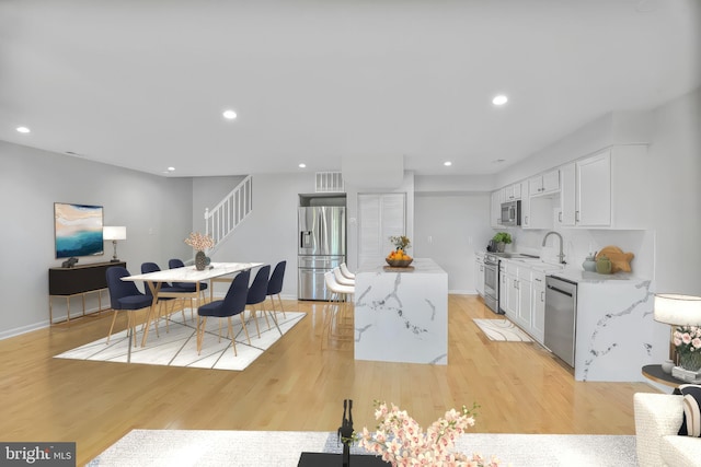 8118 Chapel Cove Dr, Laurel, MD 20707 - kitchen with stainless steel appliances, white cabinetry, a kitchen island, light wood-style floors, and baseboards