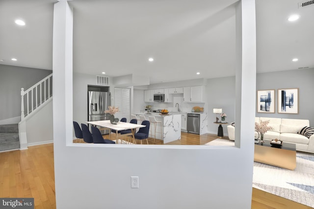 8118 Chapel Cove Dr, Laurel, MD 20707 - kitchen with appliances with stainless steel finishes, a sink, white cabinetry, light wood-style flooring, and a center island