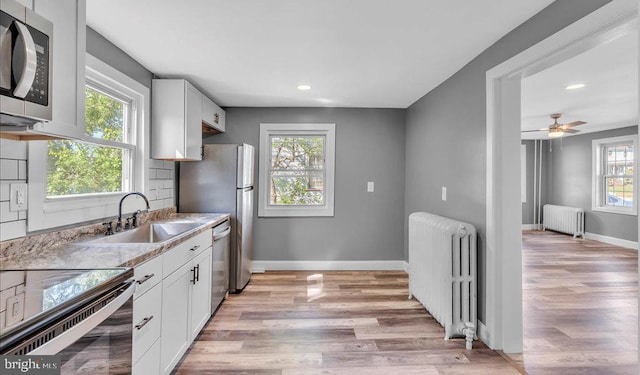 212 Broad St, Elmer, NJ 08318 - kitchen featuring radiator heating unit, stainless steel appliances, a sink, light wood-style flooring, and recessed lighting
