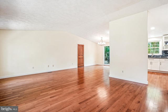 958 Tympani, Herndon, VA 20170 - unfurnished living room featuring a chandelier, light wood-type flooring, a sink, lofted ceiling, and baseboards