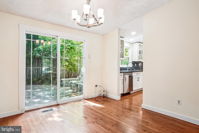 958 Tympani, Herndon, VA 20170 - unfurnished dining area with light wood finished floors, a chandelier, baseboards, and a textured ceiling