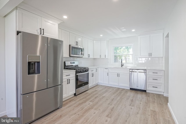 110 3rd St, Brooklawn, NJ 08030 - kitchen featuring stainless steel appliances, a sink, tasteful backsplash, light wood-style flooring, and white cabinets