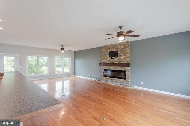 6081 Dotts Ln, Penn Laird, VA 22846 - unfurnished living room with a ceiling fan, a stone fireplace, wood finished floors, and baseboards