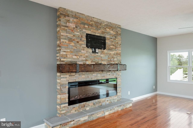 6081 Dotts Ln, Penn Laird, VA 22846 - unfurnished living room featuring a stone fireplace, wood-type flooring, and baseboards