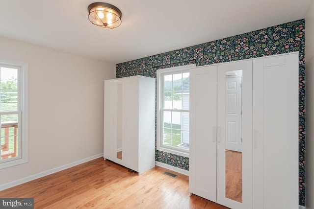 6081 Dotts Ln, Penn Laird, VA 22846 - unfurnished bedroom with wallpapered walls, light wood-style flooring, baseboards, and an accent wall