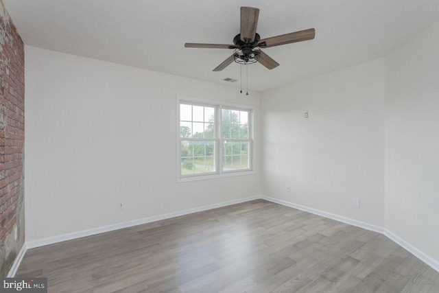 6081 Dotts Ln, Penn Laird, VA 22846 - spare room with wood finished floors, ceiling fan, baseboards, and brick wall