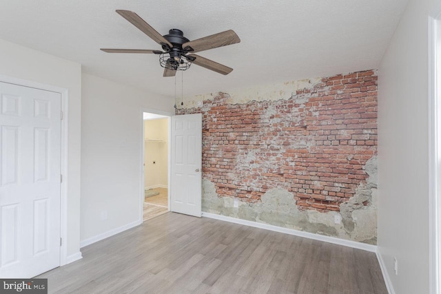 6081 Dotts Ln, Penn Laird, VA 22846 - unfurnished room with wood finished floors, brick wall, a ceiling fan, and baseboards