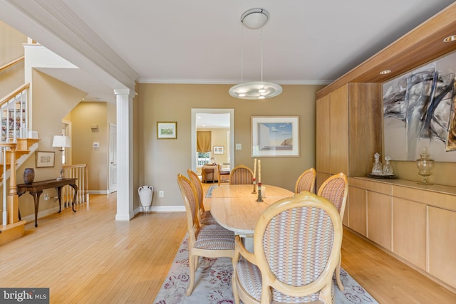 1015 Riverview Ln, Conshohocken, PA 19428 - dining area featuring light wood-style flooring, crown molding, stairs, decorative columns, and baseboards
