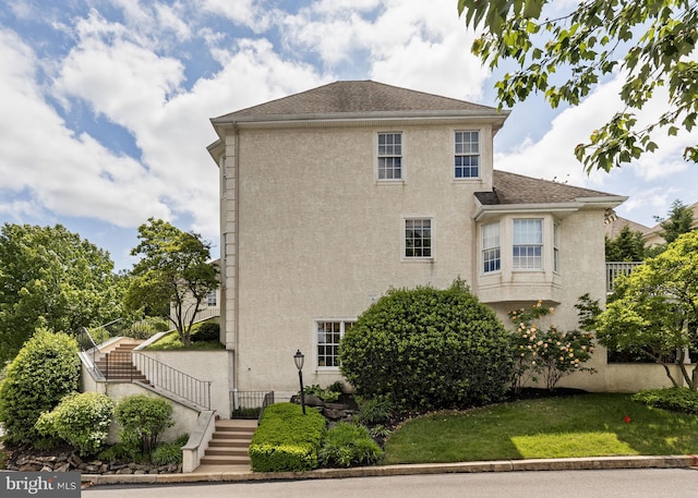1015 Riverview Ln, Conshohocken, PA 19428 - back of property with stucco siding, stairway, roof with shingles, and a lawn