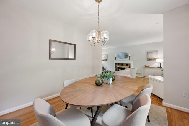 3538 Yuma St NW, Washington, DC 20008 - dining room with baseboards, a chandelier, a brick fireplace, and light wood finished floors