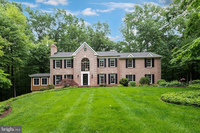 6323 Colchester Rd, Fairfax Station, VA 22039 - view of front facade featuring a chimney, a front lawn, brick siding, and view of scattered trees
