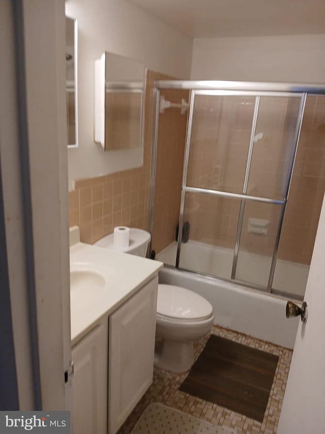 9900 Georgia Ave Unit 27-709, Silver Spring, MD 20902 - full bathroom featuring tile walls, vanity, shower / bath combination with glass door, toilet, and a wainscoted wall
