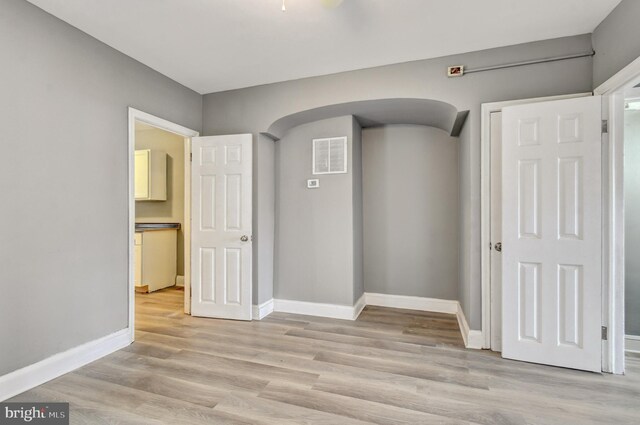 2726 E Preston St, Baltimore, MD 21213 - empty room with baseboards, light wood-style flooring, and arched walkways