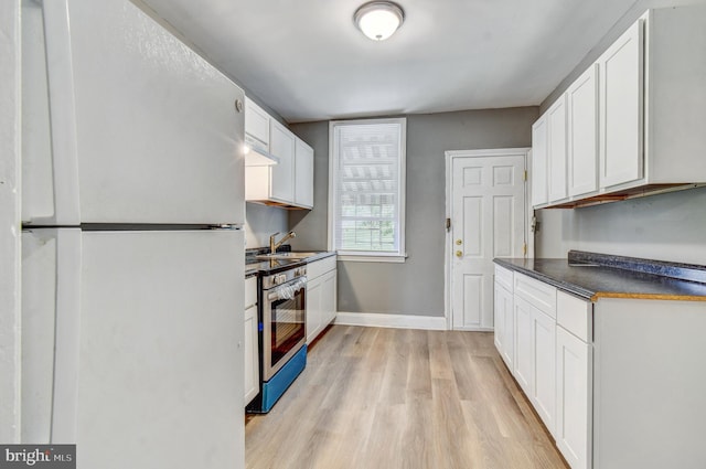 2726 E Preston St, Baltimore, MD 21213 - kitchen featuring freestanding refrigerator, stainless steel range with electric cooktop, dark countertops, light wood finished floors, and baseboards
