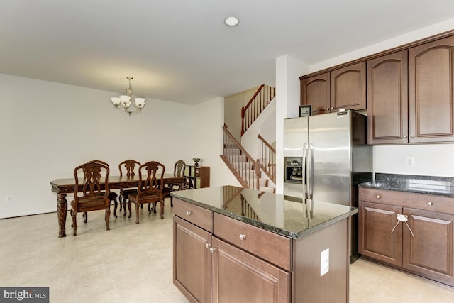 22672 Flowing Spring Sq, Brambleton, VA 20148 - kitchen with stainless steel fridge, a kitchen island, a chandelier, dark stone counters, and pendant lighting