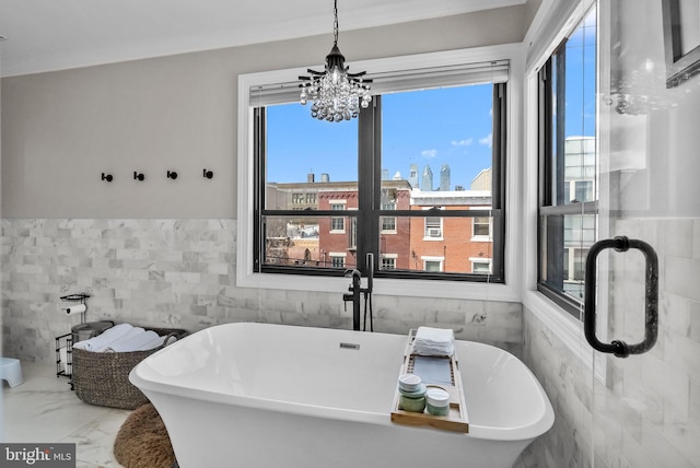 1001 S Chadwick St, Philadelphia, PA 19146 - full bathroom with tile walls, a freestanding bath, a chandelier, wainscoting, and marble finish flooring