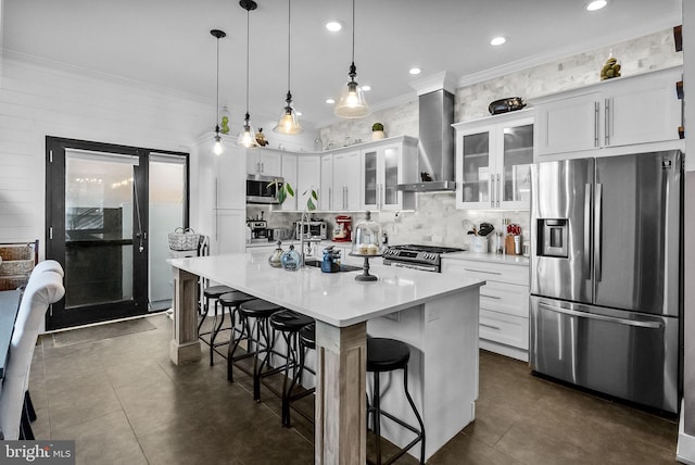 1001 S Chadwick St, Philadelphia, PA 19146 - kitchen featuring stainless steel appliances, wall chimney exhaust hood, tasteful backsplash, white cabinets, and a kitchen breakfast bar