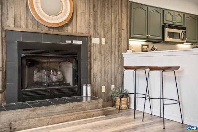 2028 Stone Rdg, Condos, Wintergreen Resort, VA 22967 - detailed view of stainless steel microwave, a tile fireplace, wood walls, and wood finished floors