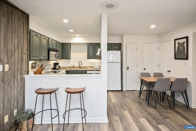 2028 Stone Rdg, Condos, Wintergreen Resort, VA 22967 - kitchen with stainless steel microwave, green cabinetry, freestanding refrigerator, a kitchen bar, and a peninsula