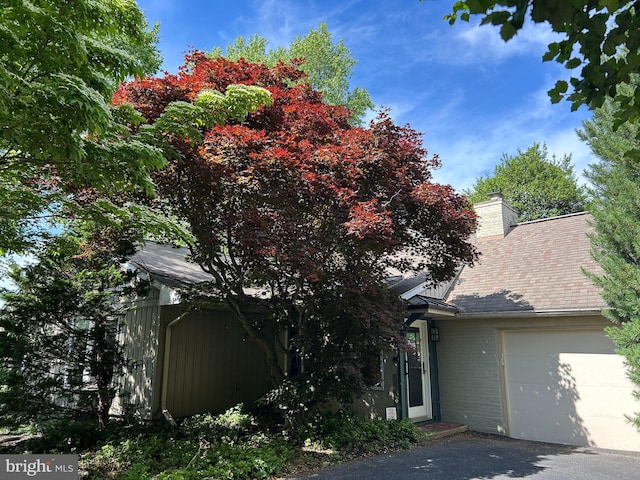 1821 Driver Ave, Lancaster, PA 17602 - view of property hidden behind natural elements featuring an attached garage, a chimney, brick siding, and a shingled roof
