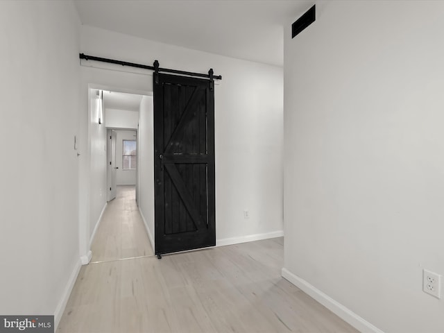2002 E Preston St, Baltimore, MD 21213 - unfurnished bedroom featuring baseboards, a barn door, and wood finished floors