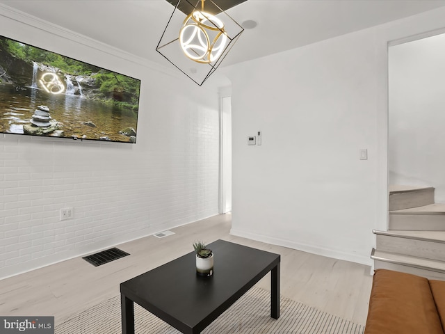 2002 E Preston St, Baltimore, MD 21213 - unfurnished living room featuring wood finished floors, baseboards, stairs, a chandelier, and brick wall