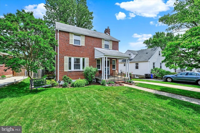 619 Warwick Rd, Baltimore, MD 21229 - view of front of house featuring a chimney, covered porch, a front yard, and brick siding