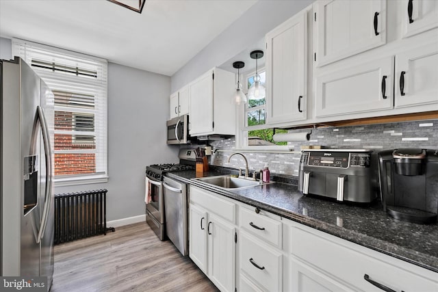 619 Warwick Rd, Baltimore, MD 21229 - kitchen featuring appliances with stainless steel finishes, radiator heating unit, a sink, white cabinets, and decorative backsplash