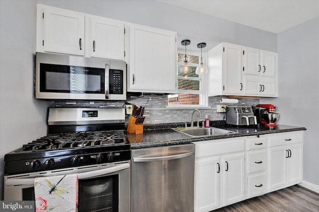 619 Warwick Rd, Baltimore, MD 21229 - kitchen with stainless steel appliances, a sink, white cabinetry, backsplash, and light wood finished floors