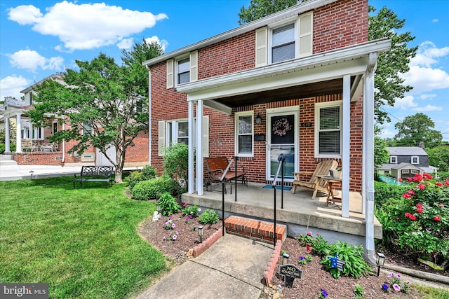 619 Warwick Rd, Baltimore, MD 21229 - view of front of home featuring covered porch, brick siding, and a front lawn