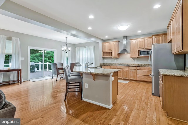 141 Lorins Dr, Huntingtown, MD 20639 - kitchen with wall chimney range hood, light wood-style flooring, stainless steel appliances, a sink, and a breakfast bar
