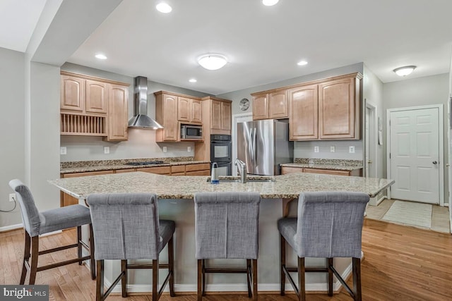 141 Lorins Dr, Huntingtown, MD 20639 - kitchen featuring wall chimney range hood, stainless steel appliances, a sink, a kitchen bar, and a kitchen island with sink