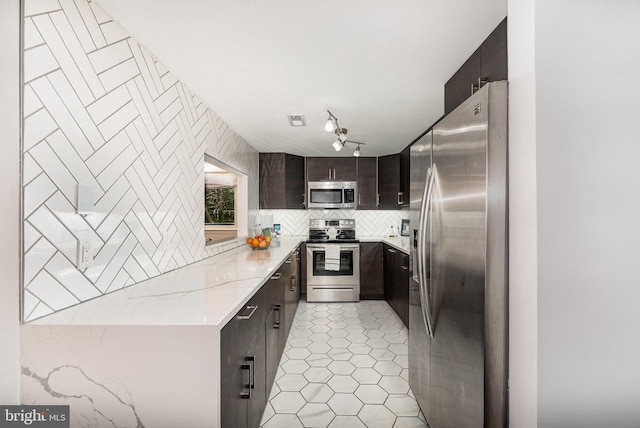 1040 Deer Ridge Dr Unit 101, Baltimore, MD 21210 - kitchen featuring stainless steel appliances, backsplash, dark brown cabinetry, light stone counters, and modern cabinets