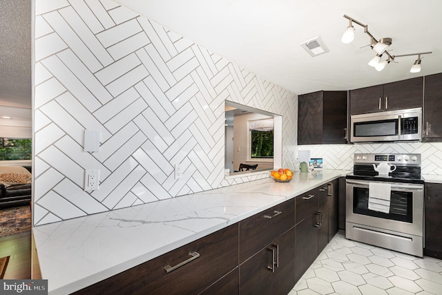1040 Deer Ridge Dr Unit 101, Baltimore, MD 21210 - kitchen featuring appliances with stainless steel finishes, backsplash, light stone countertops, and dark brown cabinetry