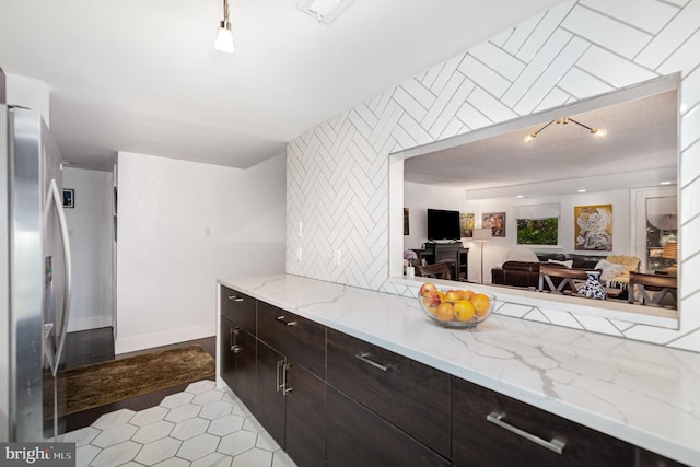 1040 Deer Ridge Dr Unit 101, Baltimore, MD 21210 - kitchen with freestanding refrigerator, dark brown cabinetry, light tile patterned flooring, rail lighting, and light stone counters