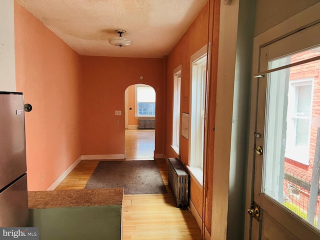735 Locust St, Reading, PA 19604 - hallway with radiator heating unit, wood finished floors, radiator, arched walkways, and a textured ceiling