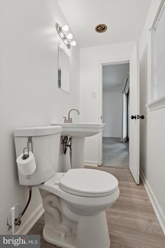 2425 W Colonial Dr, Upper Chichester, PA 19061 - half bathroom with toilet, wood finished floors, and baseboards
