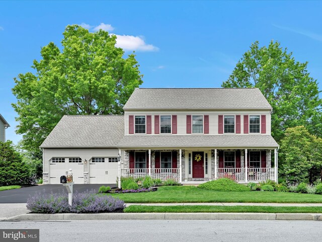 15 Behrens Dr, Palmyra, PA 17078 - colonial-style house featuring a porch, a garage, driveway, a front lawn, and roof with shingles