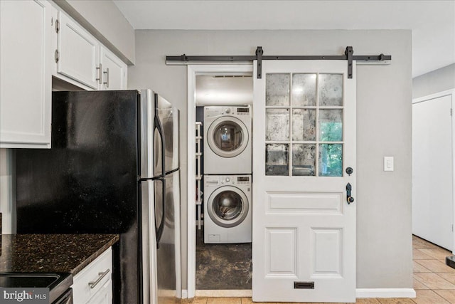963 Breakwater Dr, Annapolis, MD 21403 - laundry room featuring stacked washer / dryer, light tile patterned flooring, and a barn door