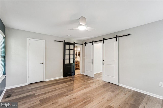 963 Breakwater Dr, Annapolis, MD 21403 - unfurnished bedroom featuring a barn door, light wood-style floors, baseboards, and a ceiling fan