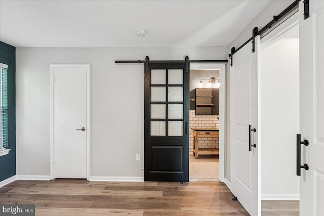 963 Breakwater Dr, Annapolis, MD 21403 - unfurnished bedroom with a barn door, wood finished floors, and baseboards