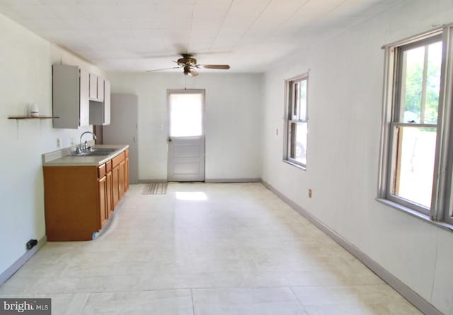 515 Burton Ave, Cambridge, MD 21613 - kitchen with a sink, a ceiling fan, brown cabinetry, baseboards, and light countertops